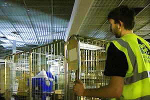 close up photo of a team 4 member dressed in a high visibility uniform pushing a caged basket with fixtures and fittings loaded onto it