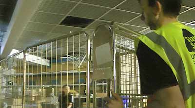 close up of a young man dressed in howarths high visibility work wear pushing a basket cage loaded with old stock